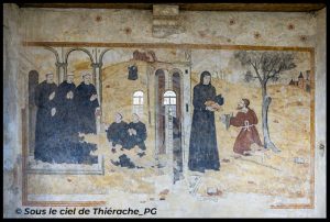 Peinture murale ancienne représentant une scène religieuse médiévale : à gauche, plusieurs moines vêtus de robes sombres se tiennent sous des arcades et prient, tandis que deux autres sont agenouillés. Au centre, une architecture avec porte et fenêtres sépare les scènes. À droite, une religieuse tend du pain à un homme agenouillé près d’un arbre, sur un paysage vallonné ponctué de bâtiments au loin. L’ensemble montre une fresque partiellement altérée par le temps, aux tons ocres et jaunes.