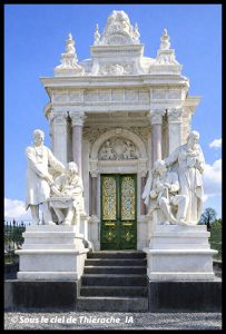 Mausolée de la famille Savart au cimetière de Saint-Michel, monument néo-classique en pierre avec fronton sculpté, colonnes et statues allégoriques encadrant l’entrée, portes ouvragées et ciel bleu en arrière-plan.