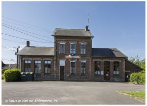 Façade de la mairie de Sommeron en Thiérache, bâtiment communal en briques rouges typiques de l’architecture thiérachienne, avec drapeau français et place du village sous un ciel bleu ensoleillé.