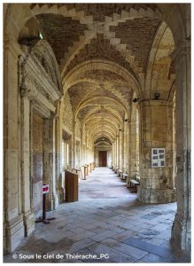 Vue intérieure du cloître de l’abbaye de Saint-Michel en Thiérache, avec sa longue galerie voûtée en pierre et briques, ses arches élégantes et sa perspective lumineuse chargée d’histoire monastique.