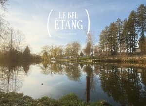 Vue paisible du camping Le Bel Étang au Nouvion-en-Thiérache, avec son étang bordé d’arbres et de verdure se reflétant dans l’eau, offrant un cadre naturel et reposant au cœur de la Thiérache.