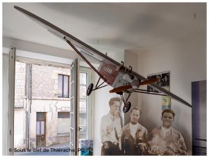 Maquette d'un avion Latécoère suspendue dans une salle du musée Jean Mermoz à Aubenton (Aisne). Cet appareil, représentatif des premiers avions de l'Aéropostale, surplombe des silhouettes de Jean Mermoz et de ses compagnons de l'épopée aérienne. À travers la fenêtre, on aperçoit la maison natale du célèbre aviateur, située juste en face du musée.
